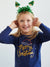 Child wearing a navy blue 'Merry Christmas' shirt with green tinsel headband on a white background