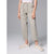 A model from the waist down wearing light beige cropped pants with a drawstring waist and side pockets, paired with beige and white sneakers, against a solid gray studio background.
