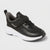Black children's sneaker with a white sole on a light gray background