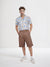 Man wearing a patterned shirt and brown shorts on a white background