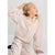 A young girl with blonde hair wearing a beige fleece half-zip hoodie and matching sweatpants, posing against a light gray background.