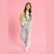 A young girl models a casual streetwear outfit consisting of a beige cardigan, white t-shirt, light gray sweatpants with a pink stripe, and white sneakers, set against a solid pink background.
