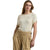 A woman modeling a short-sleeve ribbed knit sweater in cream, paired with tan high-waisted trousers, against a plain white background.