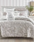 Neatly made bed with floral bedding and decorative pillows in a bedroom setting.