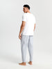 Man wearing a white t-shirt and light gray pants on a white background