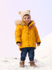 Child wearing a yellow winter coat with bear ears in the snow