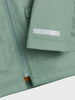 Close-up of a green jacket with a zipper and label on a white background