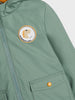 Green jacket with a dinosaur patch and button on a white background