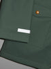 Close-up of a green jacket with a button and label on a light gray background
