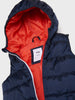 Navy puffer vest with red interior lining on a white background