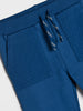 Blue jogger pants with textured pocket and drawstring on a light gray background