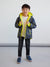 Child wearing a blue and yellow jacket with a white background