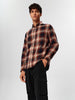 Man wearing a plaid shirt and black pants on a white background