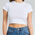 Person wearing a white crop top and blue jeans on a plain background