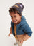 Child wearing a blue and brown jacket with a hood on a white background