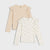 Two long-sleeve girls' tops by UGG, displayed as a set on a light gray background. The top on the left is a solid light beige with ruffled shoulders.