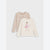 Two long-sleeve children's shirts in soft neutral tones, shown overlapping on a light gray background. The back shirt is a pale blush-beige with cursive script text, and the front shirt is off-white with a pink ballerina illustration and small text.