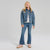A young girl modeling a blue denim jacket and matching blue denim flare jeans, styled with a white striped t-shirt and pink sneakers, against a light gray studio background.