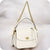 A small white leather shoulder bag with a gold chain strap, top handle, and gold-tone turn-lock closure, photographed against a soft light gray background.
