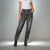 A model wearing high-waisted, wide-leg charcoal gray washed jeans, a white ribbed short-sleeve top, and black ankle boots with white polka dots, standing against a light gray studio background.