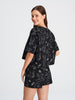 Woman wearing a black dress with white patterns on a white background