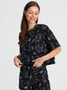 Woman wearing a black dress with white abstract patterns on a white background