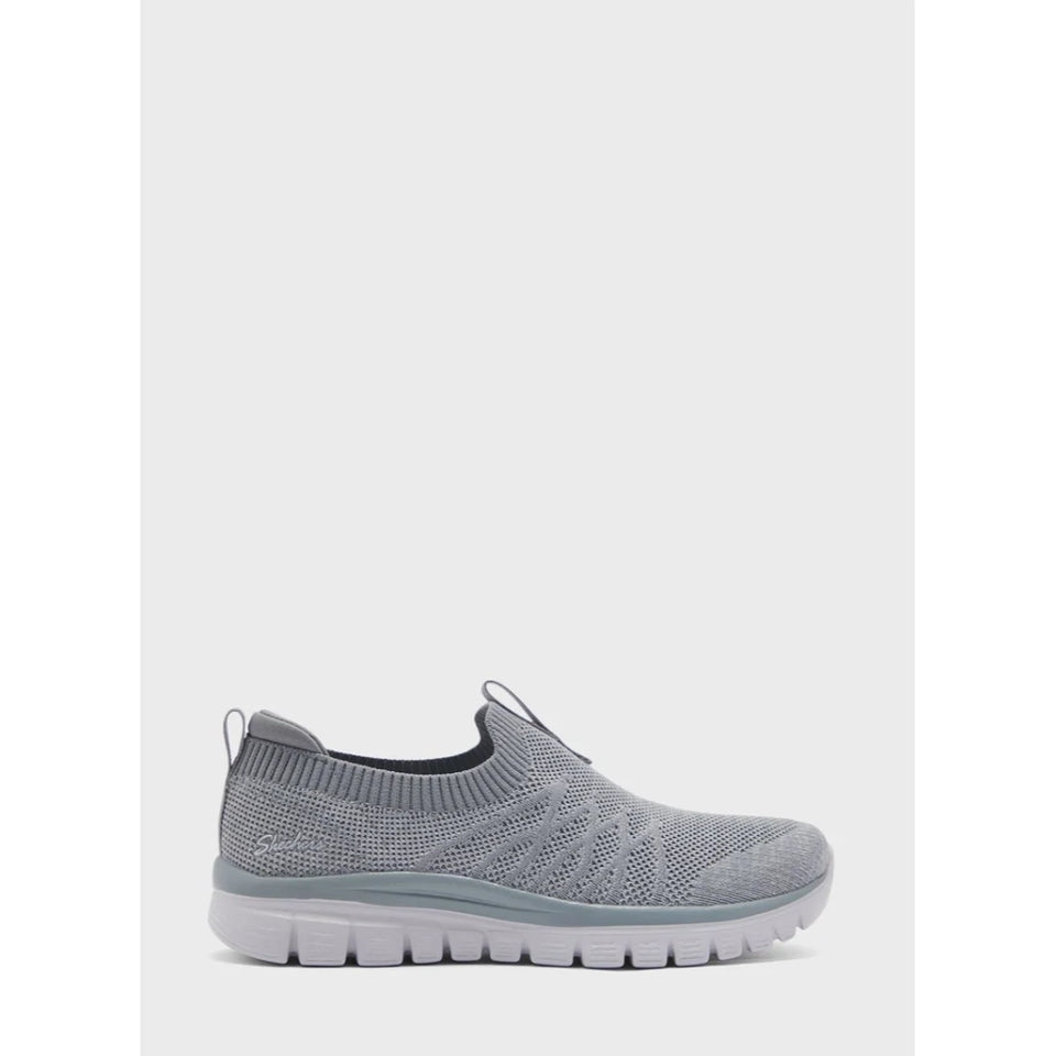 A light gray knit slip-on sneaker with a flexible white sole, shown from a side profile against a light gray background.