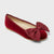 A single red velvet flat shoe with a matching fabric bow on the toe, shown from a three-quarters angle against a light gray background.
