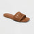 Brown sandal with woven design on a light gray background