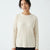 A woman wearing a cream-colored ribbed knit sweater with a crew neck, shown from the waist up against a plain white background.