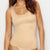 A woman wearing a seamless, scoop-neck beige bodysuit or shapewear top against a plain white background.