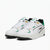 A pair of white low-top sneakers with green, black, and gold accents, displayed on a light gray background.