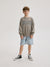 Child wearing a 'Sports Club' sweatshirt and denim shorts on a plain background