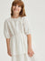 Young girl wearing a white dress against a plain background