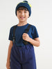Child wearing a blue outfit with suspenders and a knit hat on a white background