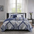 Navy and white patterned comforter set on a bed in a bedroom with a window and side table.