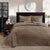 Brown textured comforter on a bed in a bedroom setting with a lamp and decor items.