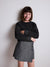 Young girl wearing a black patterned sweater and gray skirt against a plain background with a cashback 20% badge.