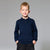 A young boy with blonde hair smiling, wearing a dark navy blue long-sleeve polo sweater and black pants, standing against a solid gray studio background.