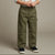 A child wearing olive green cargo pants with side flap pockets, paired with a white shirt and navy blue sneakers, standing against a neutral beige studio background.