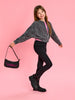 Young girl holding a black handbag with pink design on a pink background