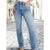 A person wearing light blue high-waisted straight-leg jeans, standing on a cobblestone street with blurred buildings in the background.