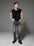 Man wearing a black sleeveless shirt and gray jeans against a gray background