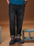 Person wearing black jeans and blue sneakers standing next to a concrete block on a brown background