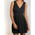 A sleeveless black wrap-style mini dress with a V-neckline and flared skirt, shown on a model against a plain light background.