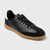 Black sneaker with a brown sole on a light gray background