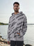 Man wearing a gray hoodie with black text pattern by a body of water