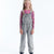 Young girl wearing gray denim overalls on a white background