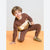 A young boy wearing a brown and beige two-piece sweatshirt and jogger set, posing on an orange floor against a light gray background.