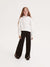 Young girl wearing a white hoodie and black pants on a white background